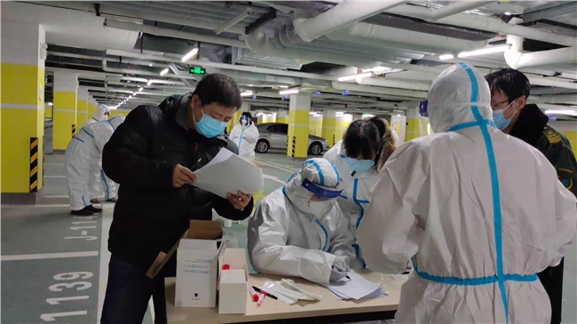 王建瓴（左一）正在与核酸检测工作人员核对信息.jpg